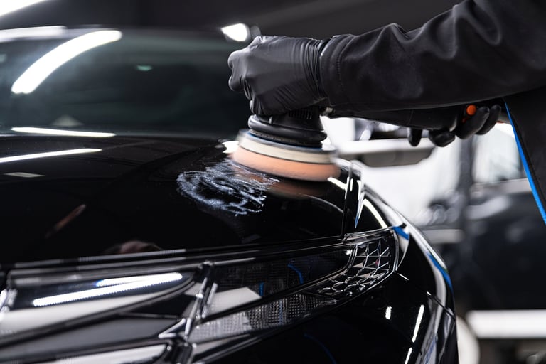 Car detailing worker removing scratches with polisher