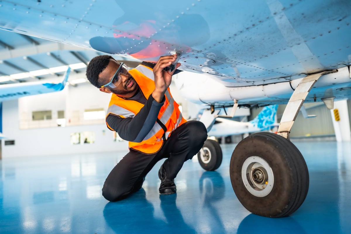 Aircraft maintenance engineer inspecting plane wing in hangar